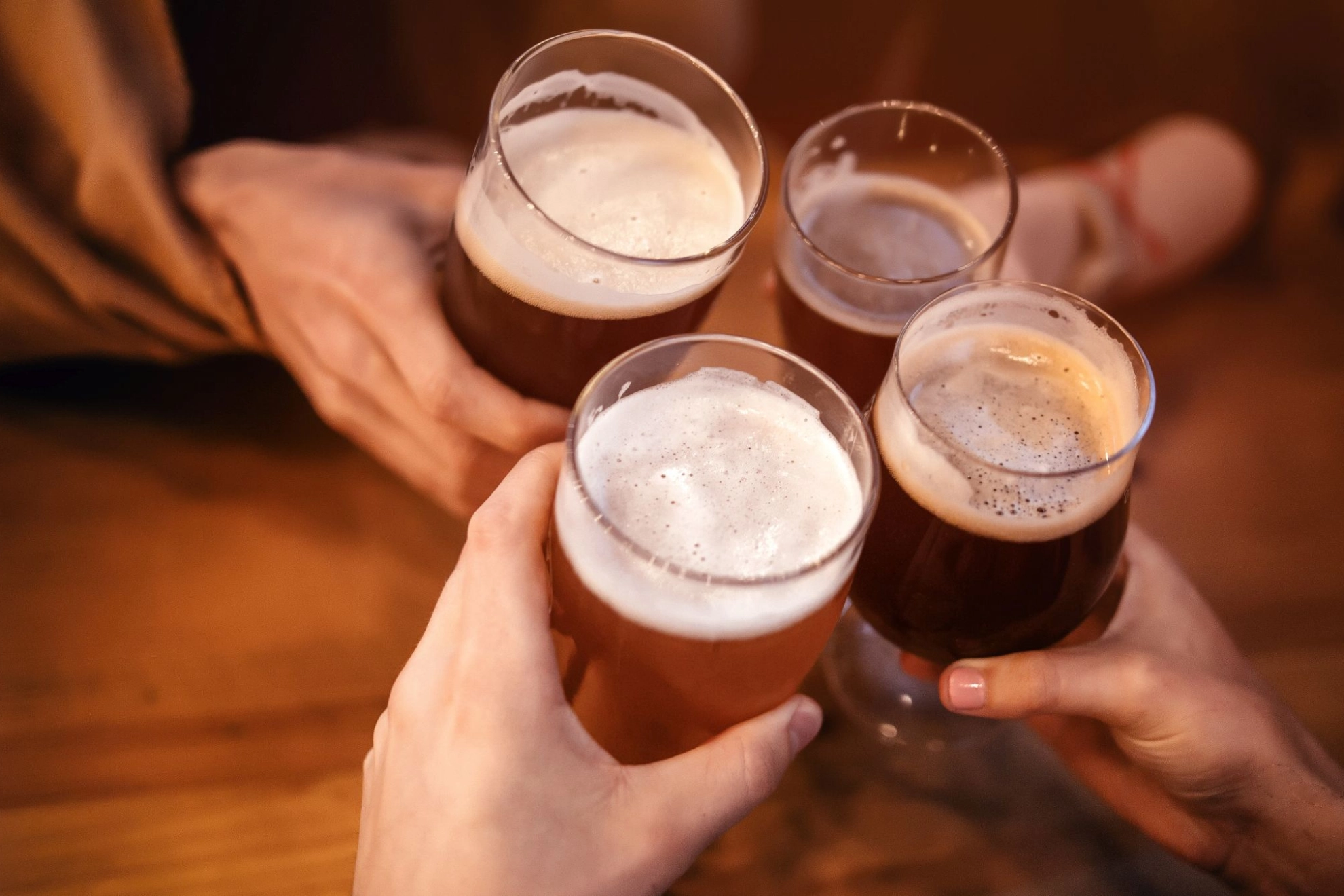 vier Menschen stoßen mit Bieren an