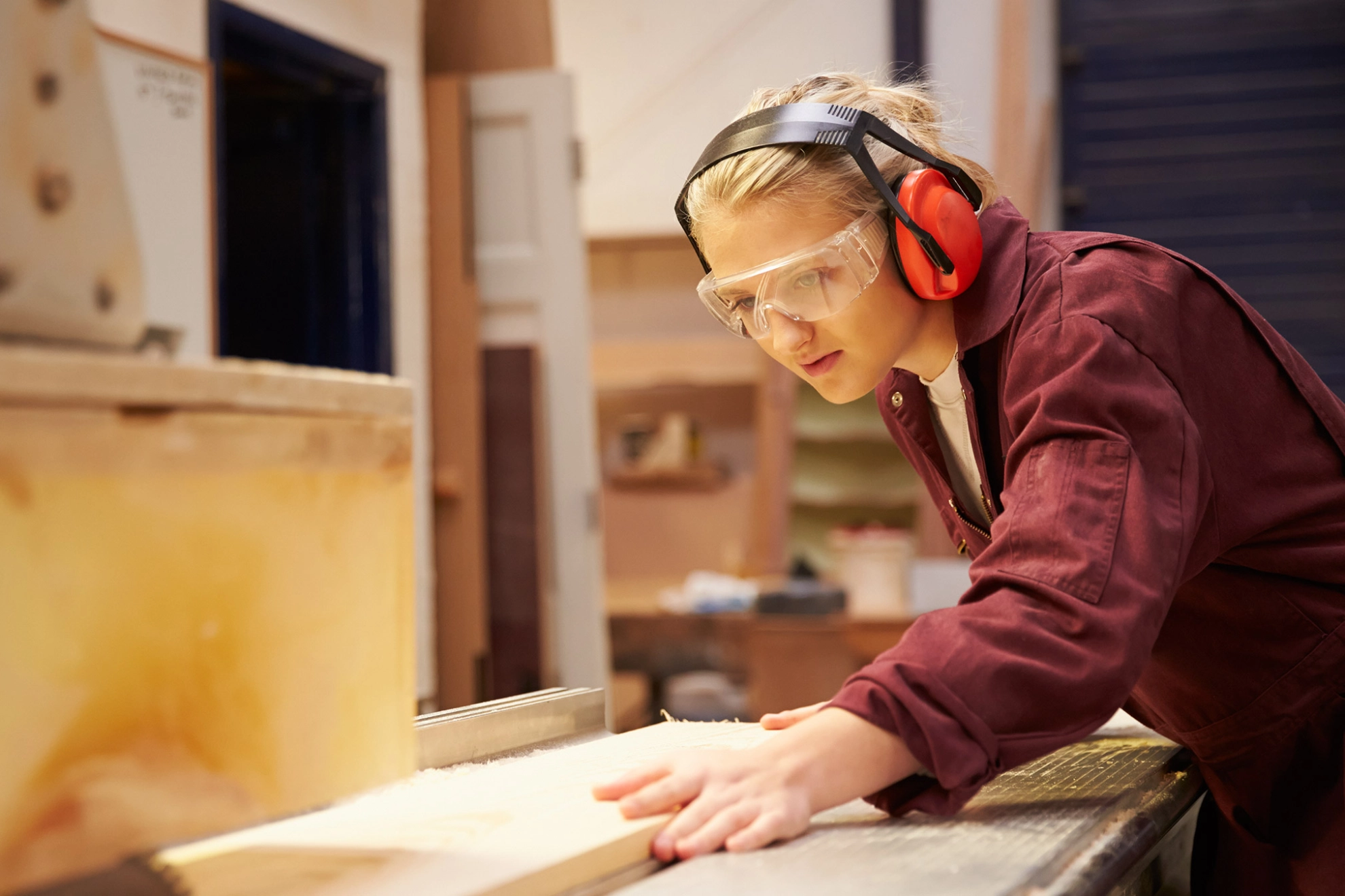 Auszubildende sägt an einer Kreissäge ein Holzbrett zurecht.