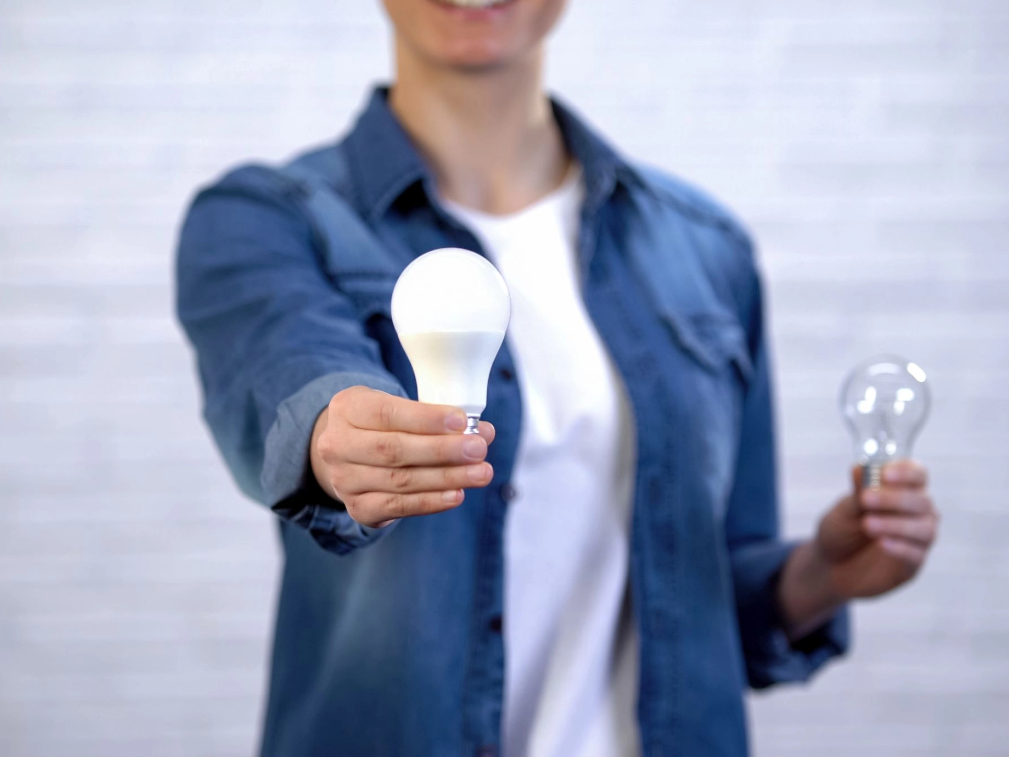 Frau wählt LED Glühbirne anstelle von Glühlampe