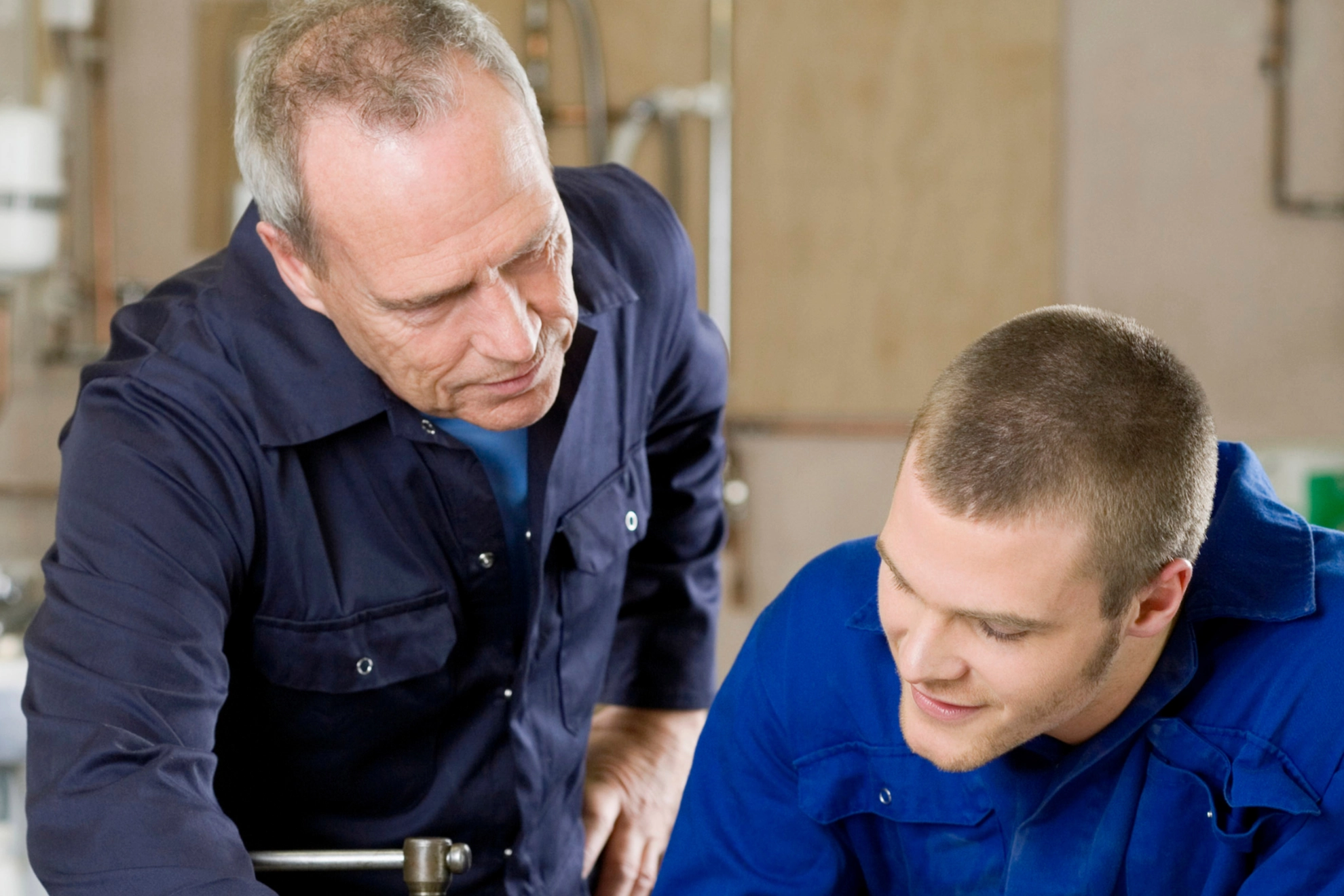 Ein Auszubildender zum Gas-Wasser Installateur bekommt von seinem Meister etwas erklärt.