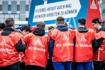 Eine Gruppe junge Männer mit roten Streikwesten.